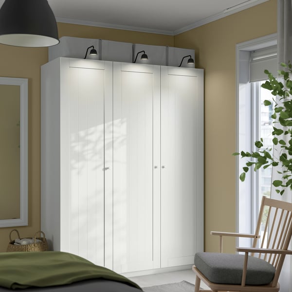 Bedroom with large white PAX wardrobe, green bed, and wooden chair.