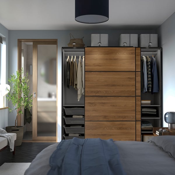 Modern bedroom featuring a PAX wardrobe with sliding doors, hanging clothes, and shelves.