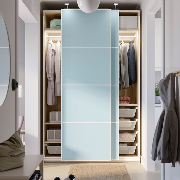 A modern closet with sliding doors and organised storage spaces. Shelves hold folded clothes and baskets, while hangers store garments.