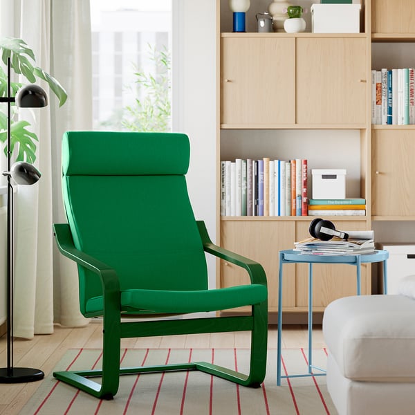 Modern living room with green POÄNG armchair, cushioned seat & high back, near blue side table, bookshelf, & striped rug.