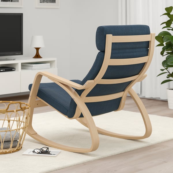 Blue cushioned rocking chair on wooden frame in living room with tv and plant.