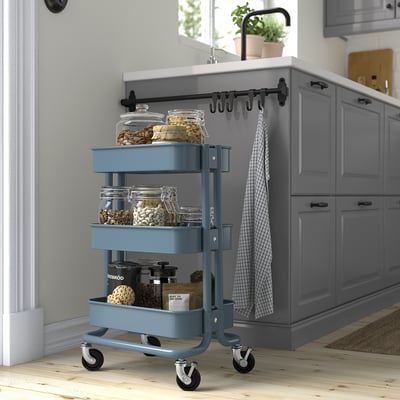Blue ikea RÅSKOG trolley in kitchen, holding jars, fits under counter.