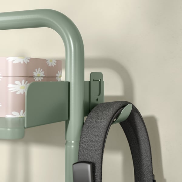 Green RELATERA desk hook holds grey headphones, designed for organising workspace.