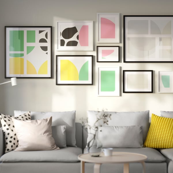 Modern living room with grey sofa, colourful art, and small wooden table with a cup.