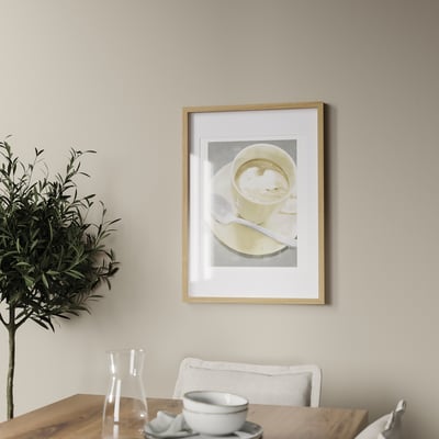 Framed a coffee cup on a wall above a table with a plant and tableware. The frame can hang vertically or horizontally.