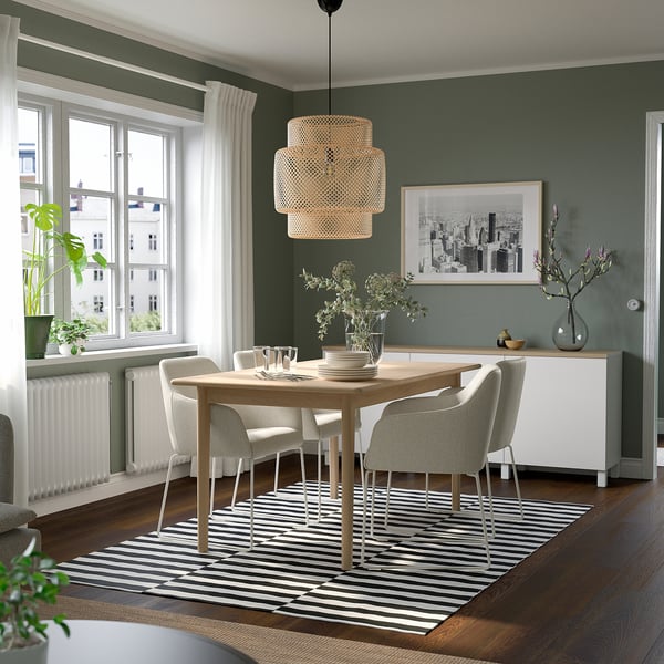 Modern dining area with SKANSNÄS extendable table for 4-6, striped rug, pendant lamp, dark green walls, white curtains, and decorated sideboard.