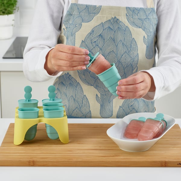 Person making popsicles using colourful moulds and an ice tray.