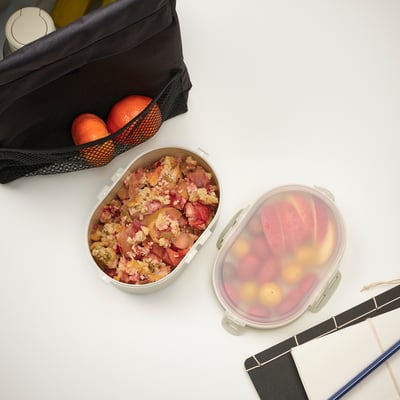 Lunch containers with fruits, grains, oranges, and notebook. Perfect for on-the-go meals.