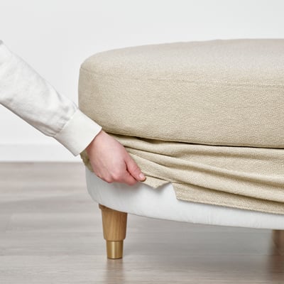 Person adjusting black and beige rounded footstool with wooden legs.