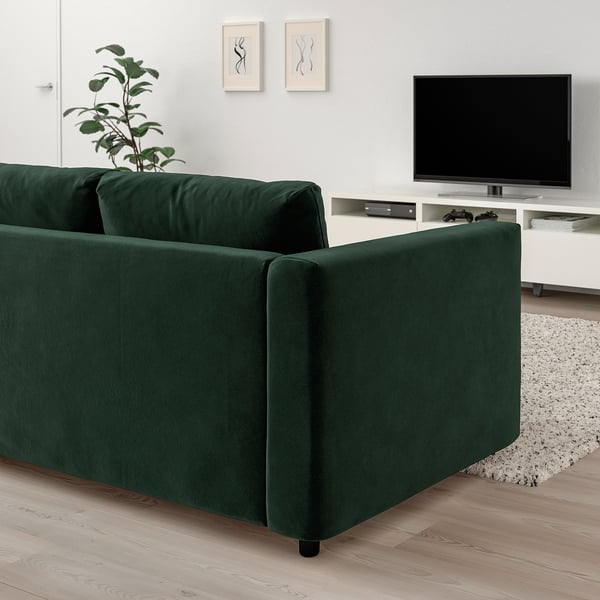 Dark green VIMLE sofa with tv, plant, white wall, and frames.