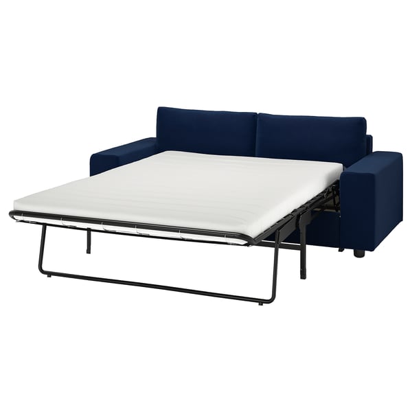 A deep blue l-shaped sofa-bed with metal frame and white mattress, sleek design.
