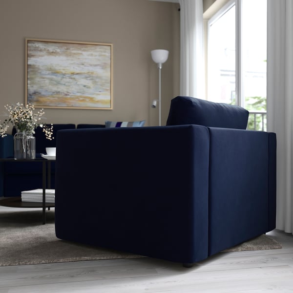 Modern living room with blue VIMLE sofa by window, decorated with abstract art and flowers.