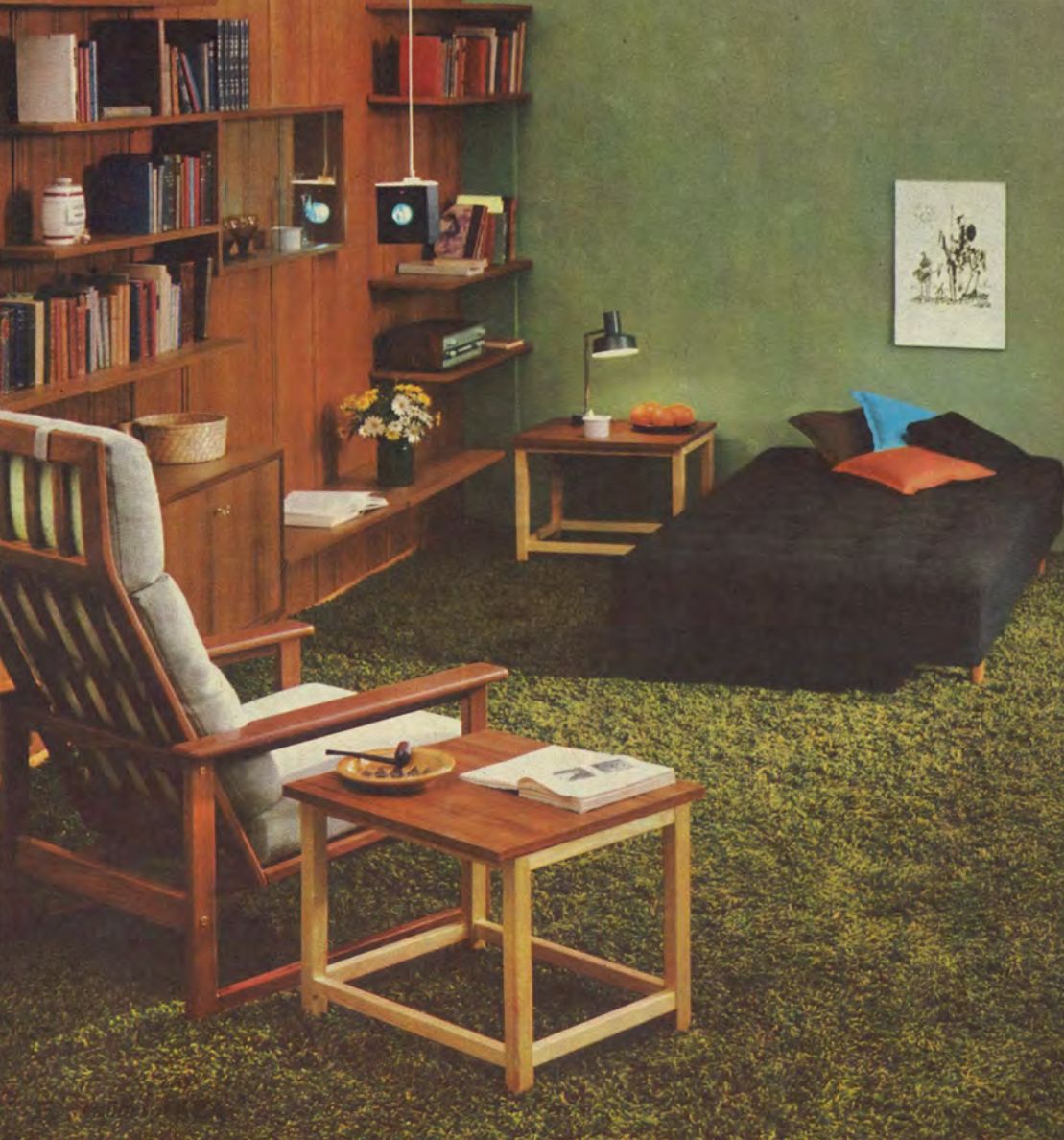 A lounge room set from 1965 with wall-to-wall shag carpet in green, and green walls; furnished with a large shelving unit, arm chair and day bed.