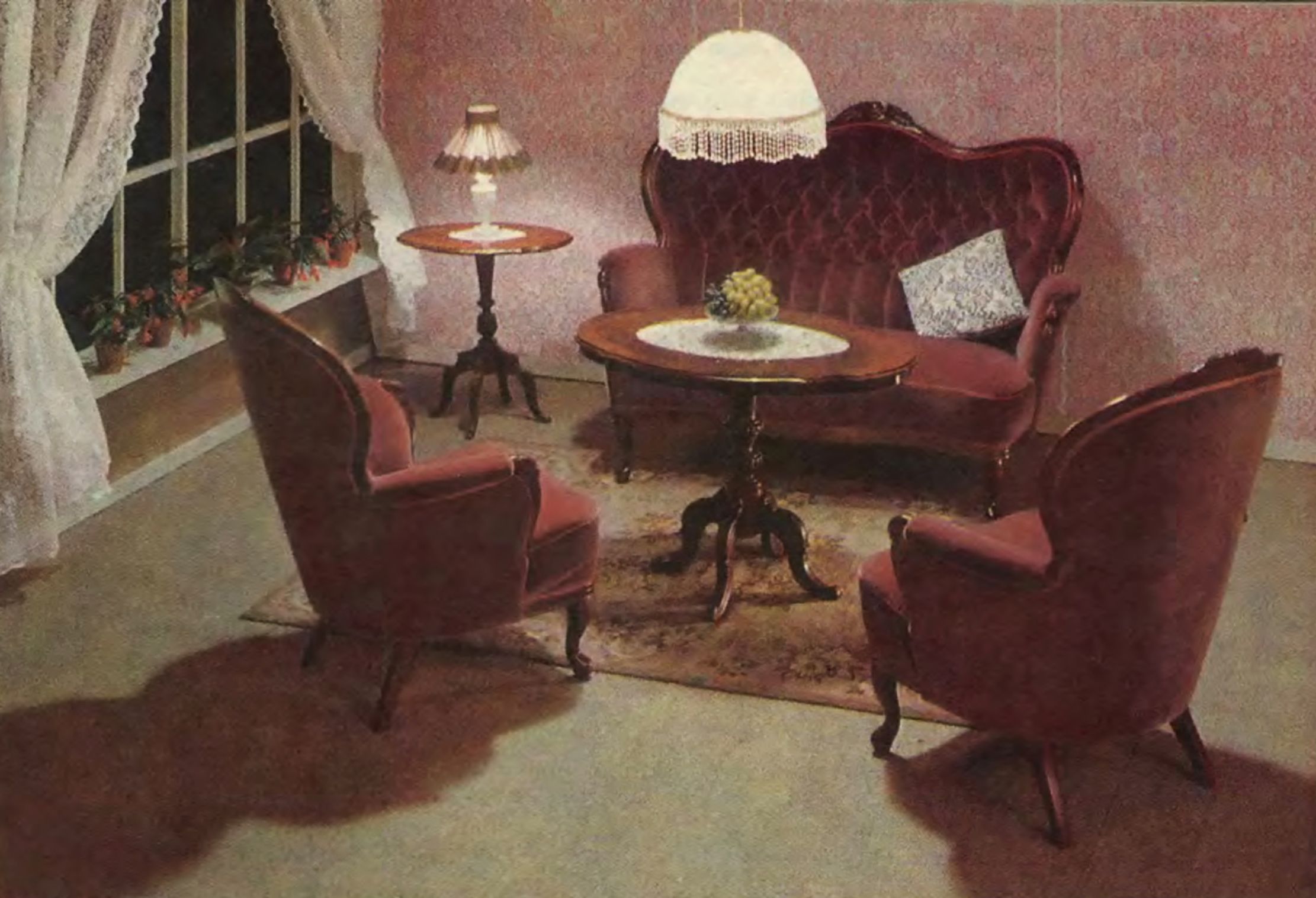 A living room with a red antique sofa, two chairs, two tables and a pendant lamp.
