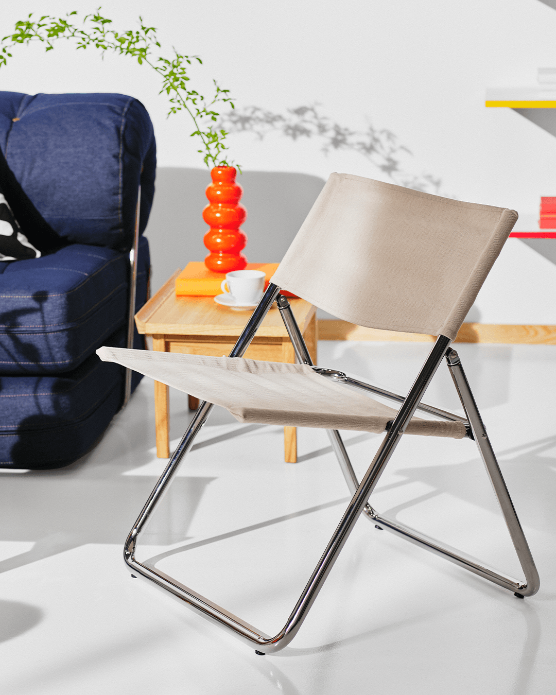 The colour cutout of the MOFALLA foldable chair transforms into a white roomset.