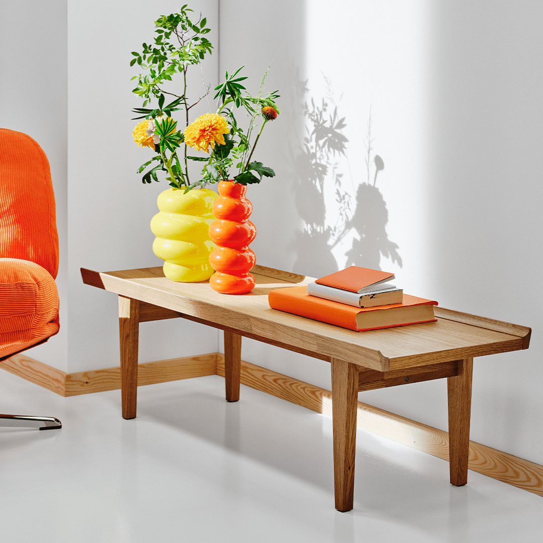 The GUTTANE coffee table with two vases and some books in a white roomset.