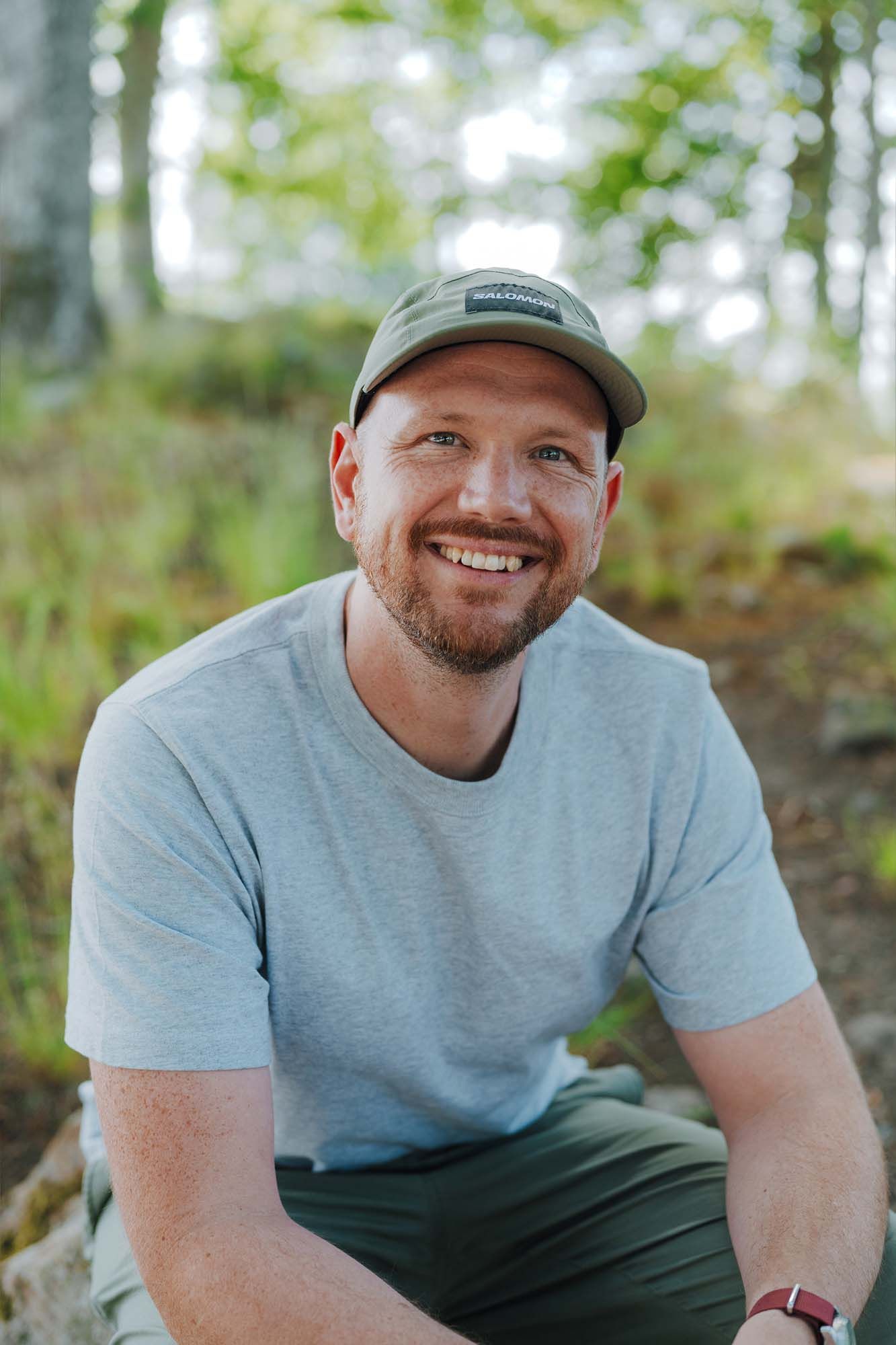 Sebastian smiles at the camera with the forest behind him.