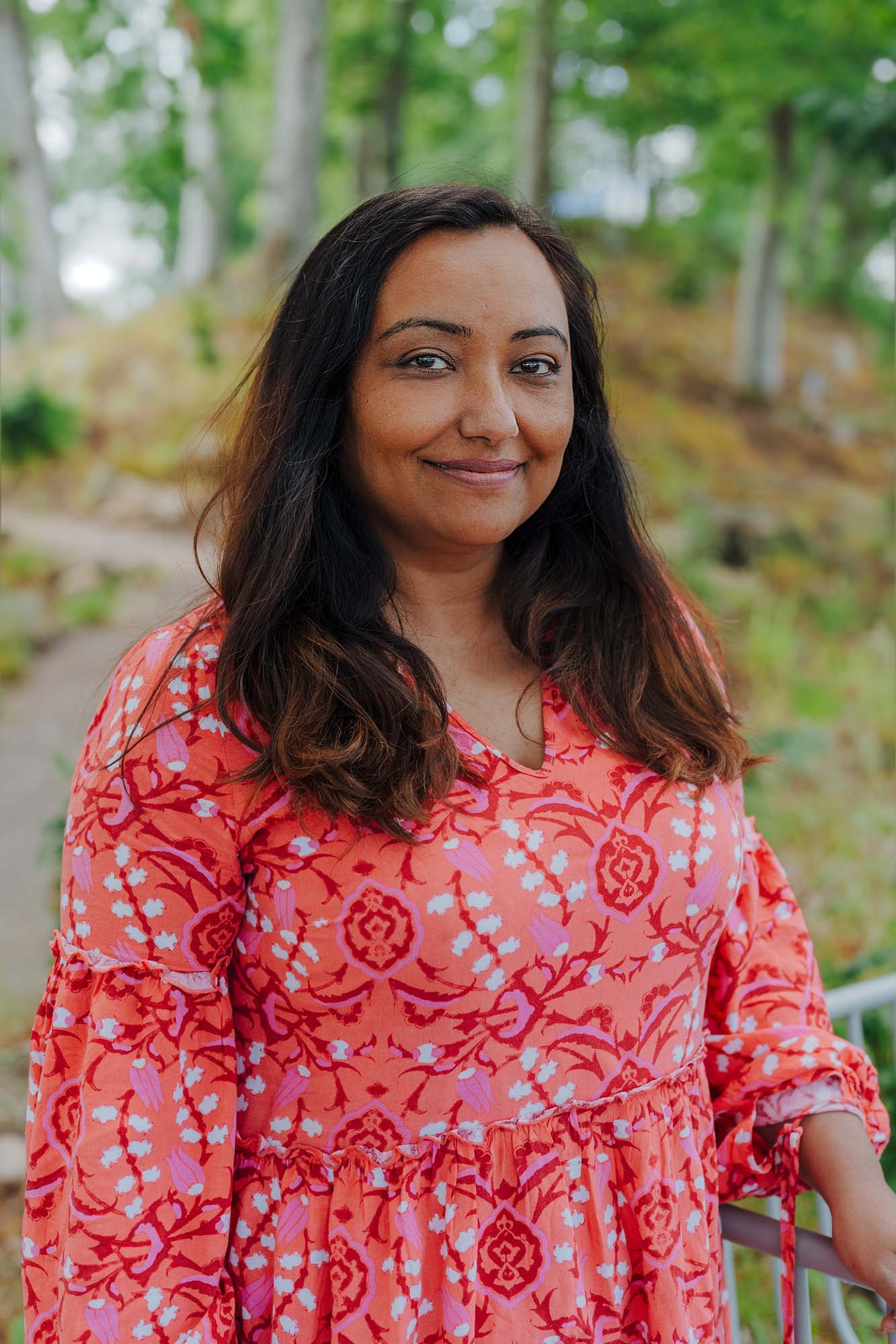 Shaveta smiles at the camera with the forest behind her. 