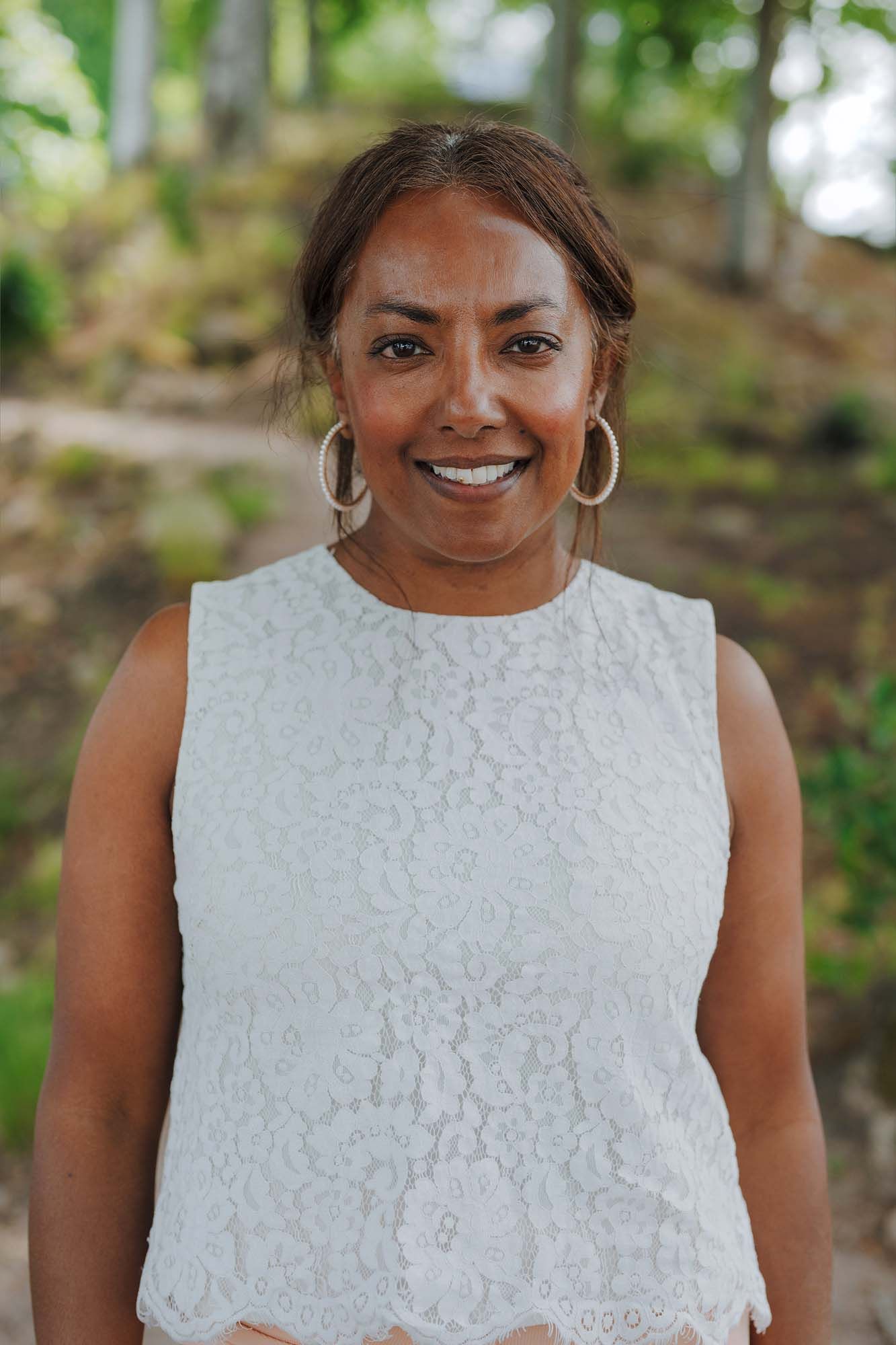 IKEA co-worker Rasika Carlsson is standing outside with trees in the background. She smiles at the camera.