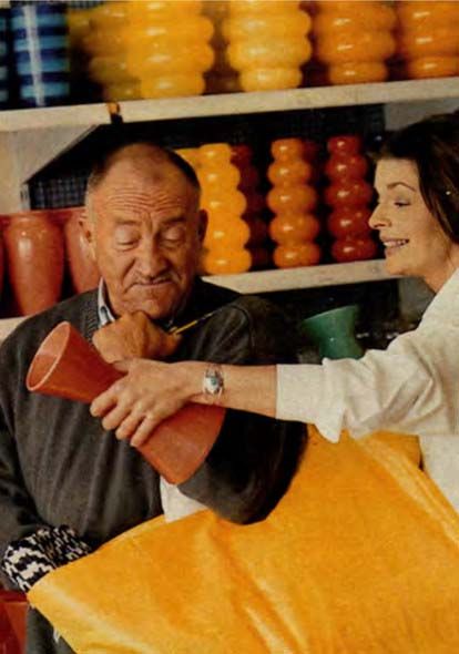 A vintage image from the 1996 IKEA catalogue of two people shopping in IKEA with a big yellow FRAKTA bag. In the background are lots of SNURRA vases stacked on shelves.