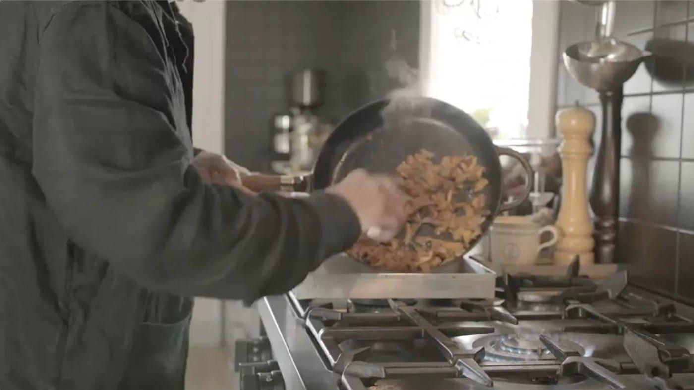A person cooks mushroom in a cast iron pan