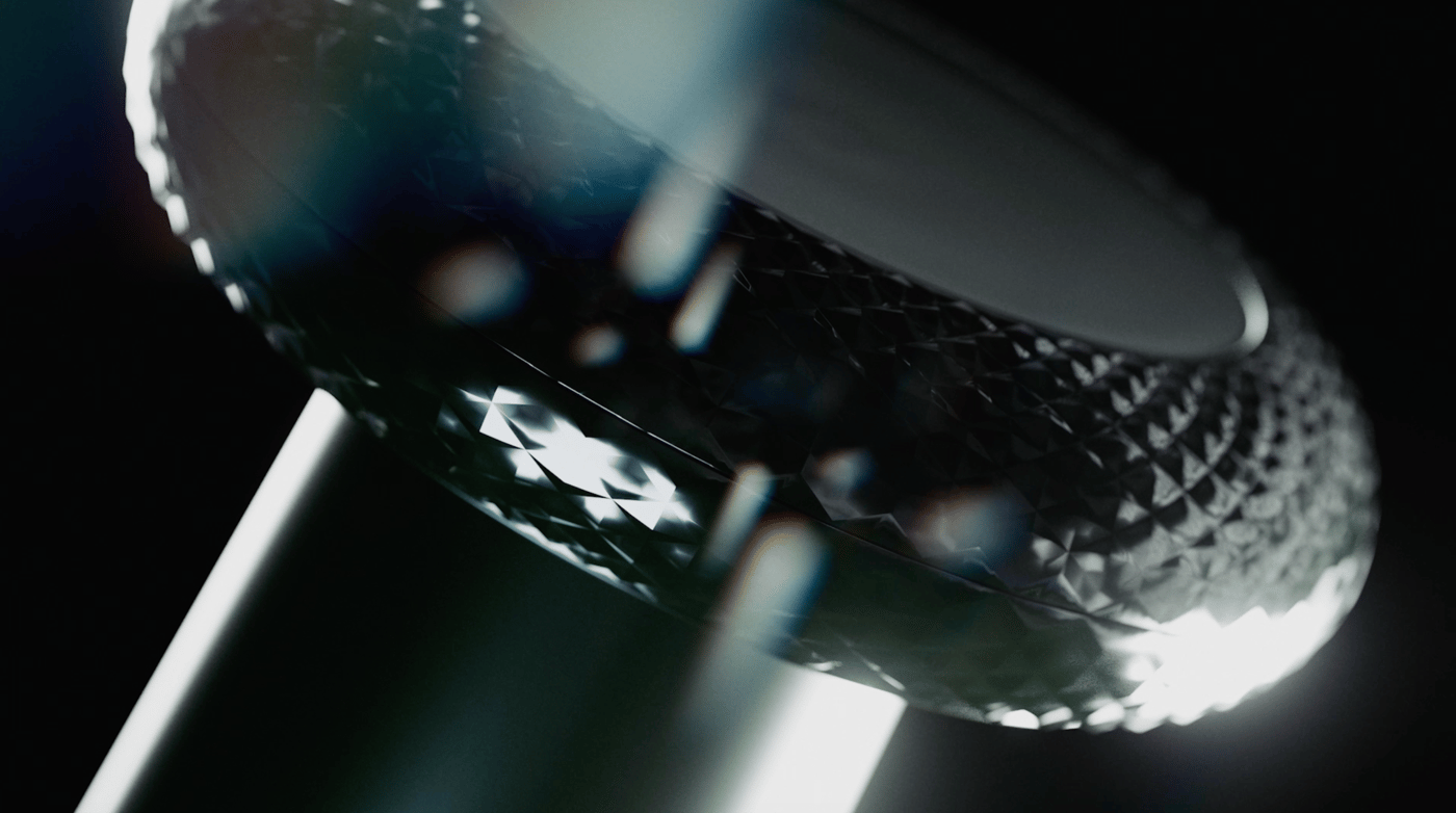 Close up image of a gaming controller thumbstick in black, against a black background with scattered light reflections.