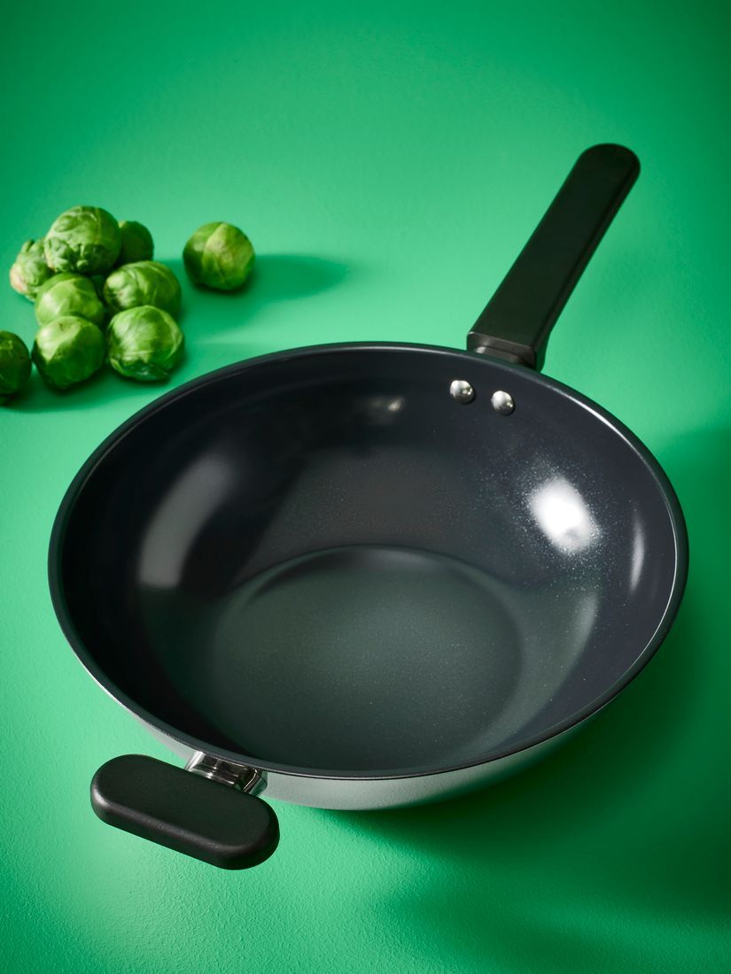 The MIDDAGSMAT pan on a green background with some brussels sprouts next to it.