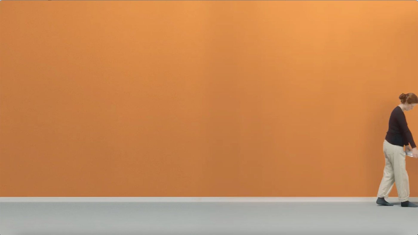 A person in front of a large orange wall.