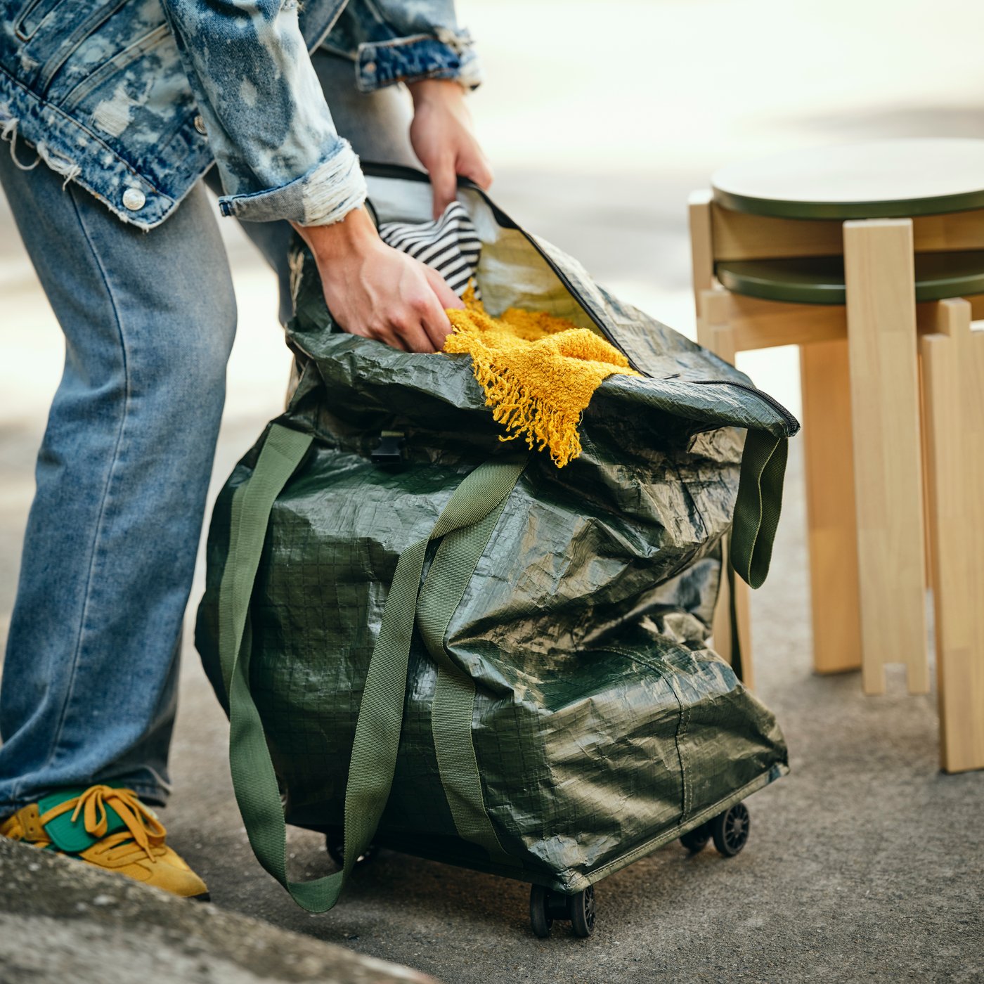 A person placing items into the large shopping bag on wheels made from 100% polypropylene and plastic. 