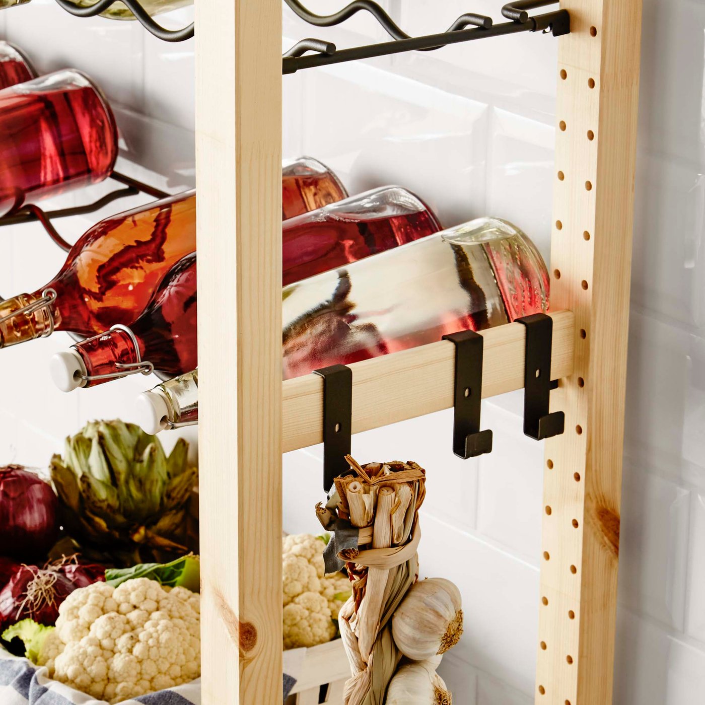 A close-up of wooden shelves with a bottle rack and black hooks attached to the side of the unit.