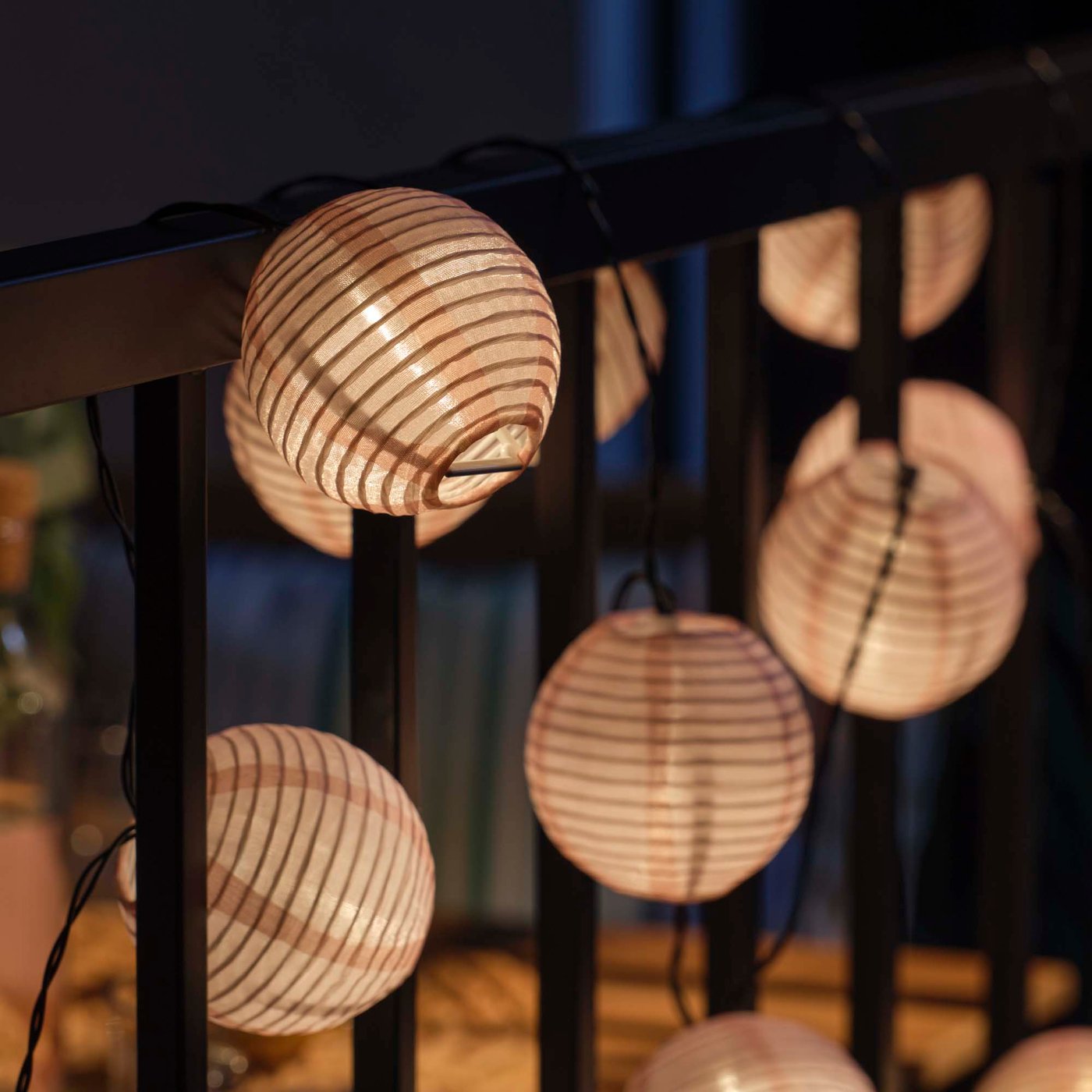 Glowing string lights are wound around a balcony railing.