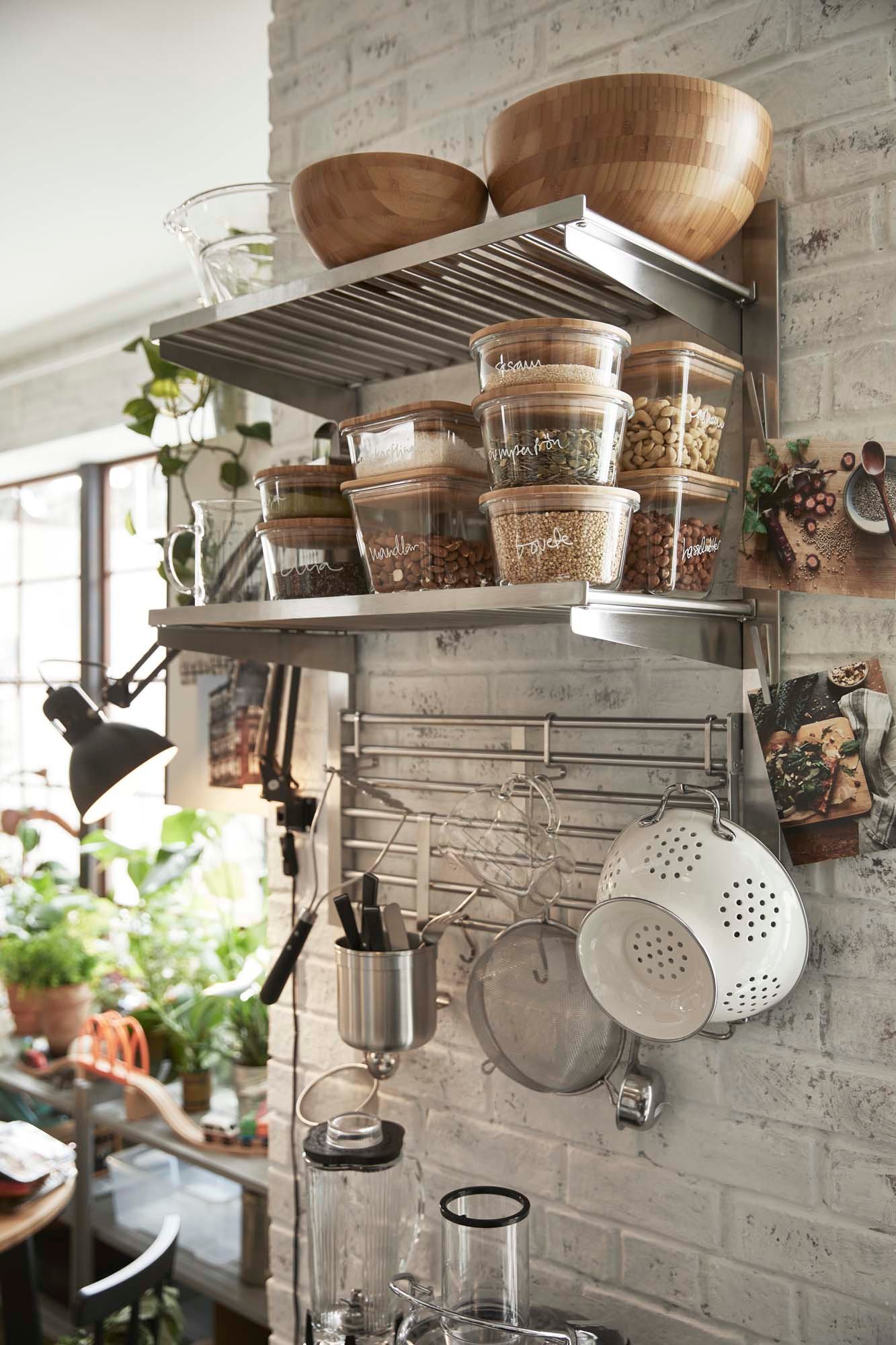Stainless steel wall mounted shelves laden with food storage jars and serving bowls.