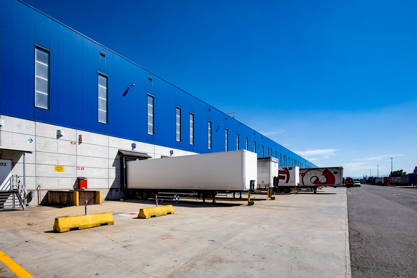 Exterior view of a large IKEA distribution centre with shipping containers lined up along the loading bays.
