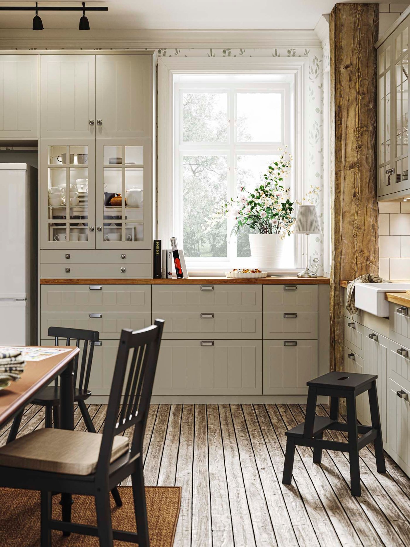 A beige STENSUND kitchen behind a dining area with black chairs.