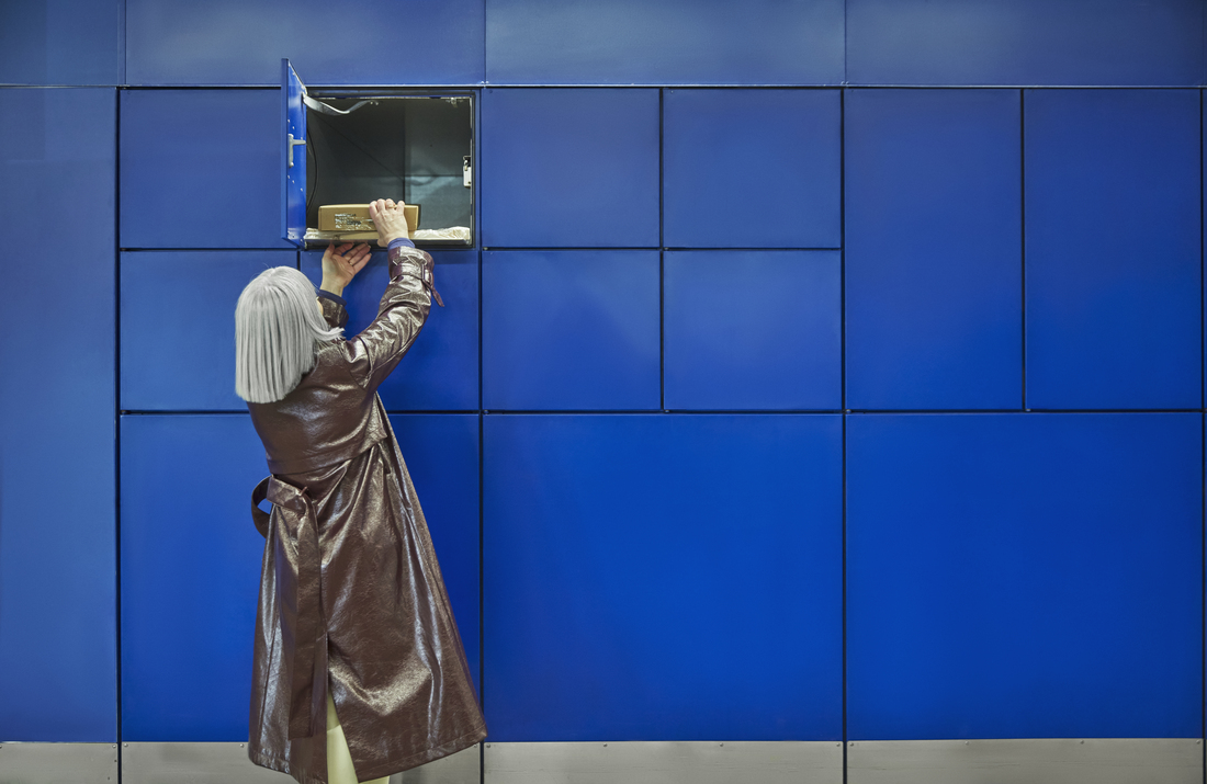 A person taking a package out of a blue locker.