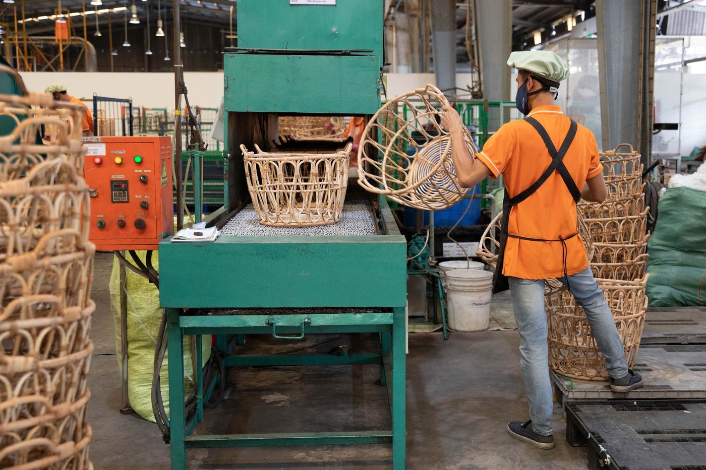 A person removes a basket from an assembly line in a factory setting.