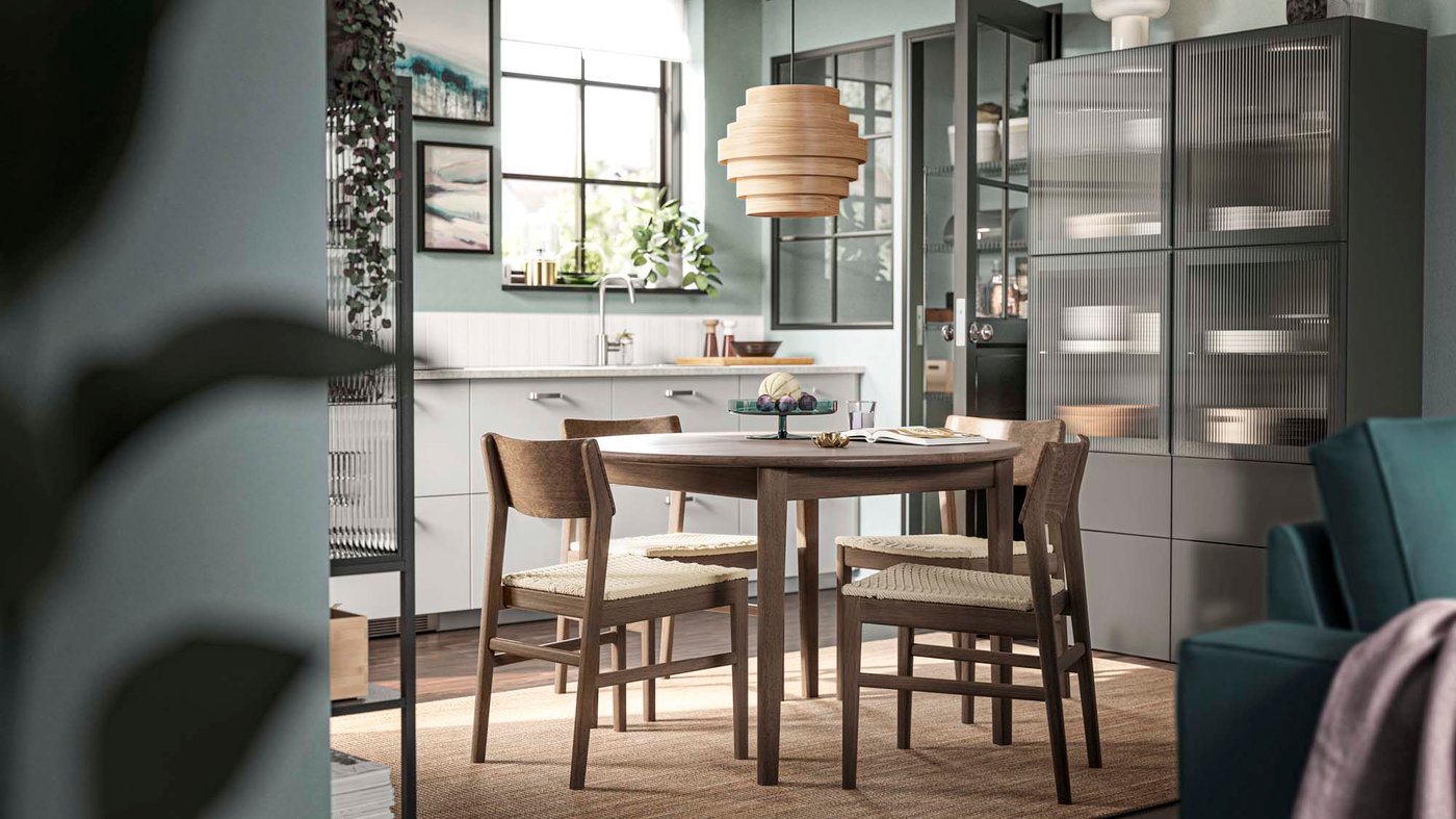 A black, green and white kitchen with a round wood table.
