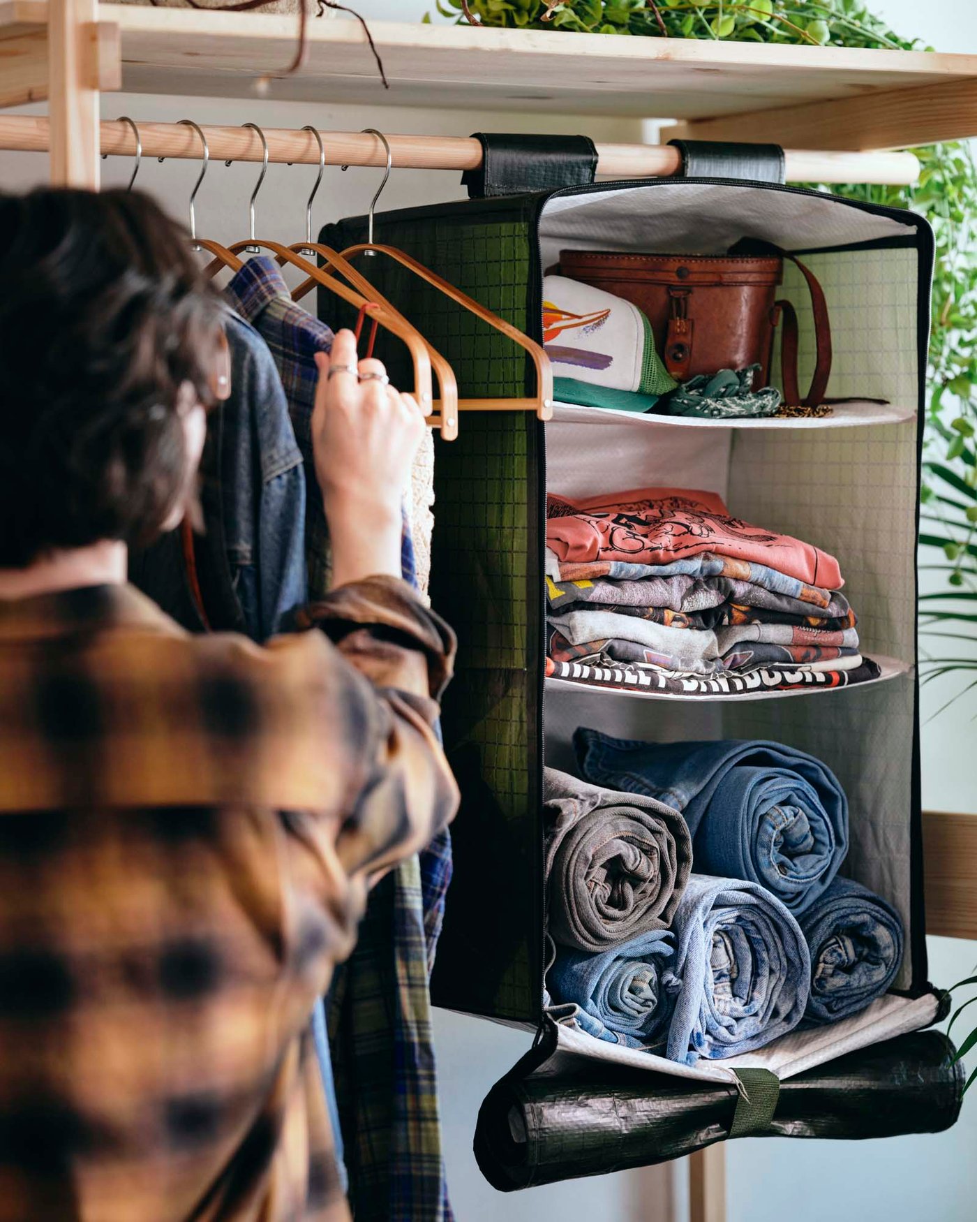 A person interacting with hanging storage with compartments full of clothes.