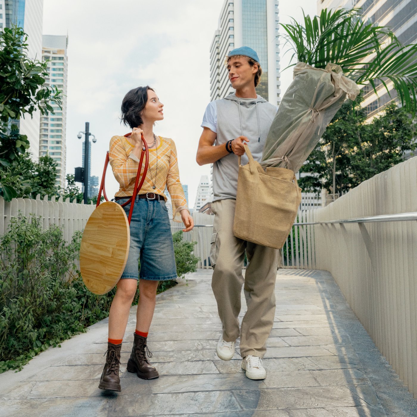 Two people walking outdoors carrying plants and home furnishing products.