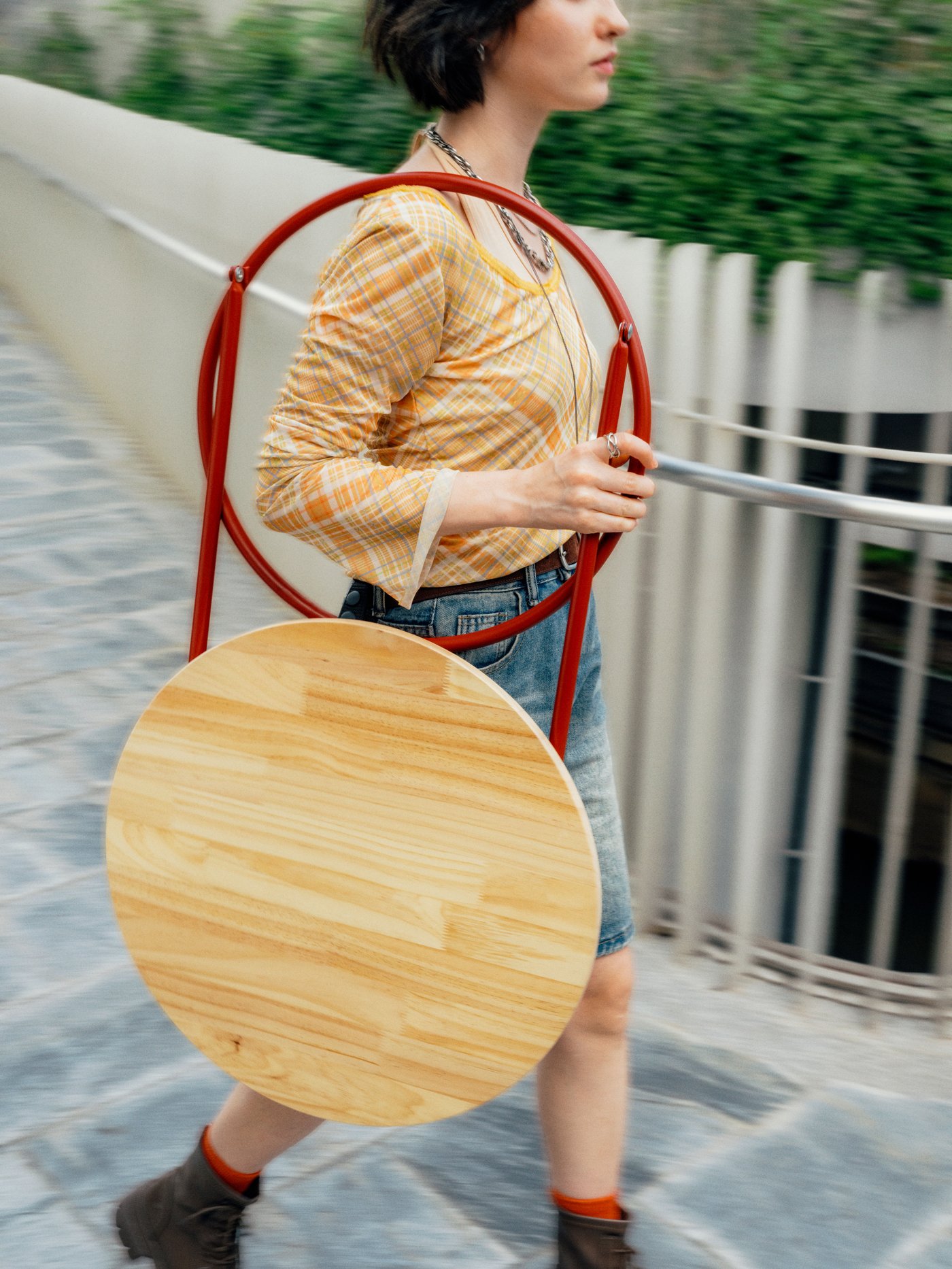 A person carrying the foldable side table while walking outdoors.