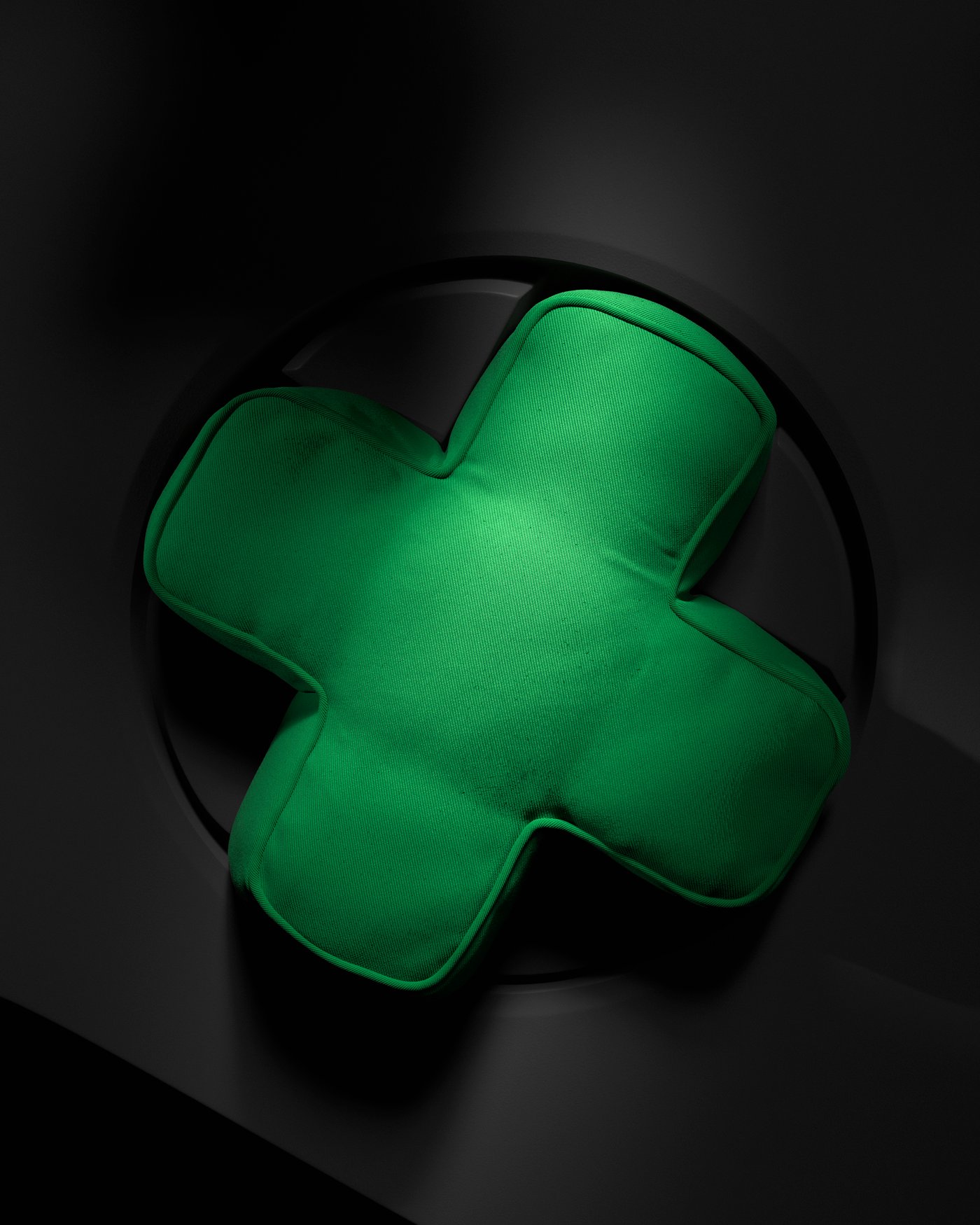 A green cross-shaped cushion viewed from above.