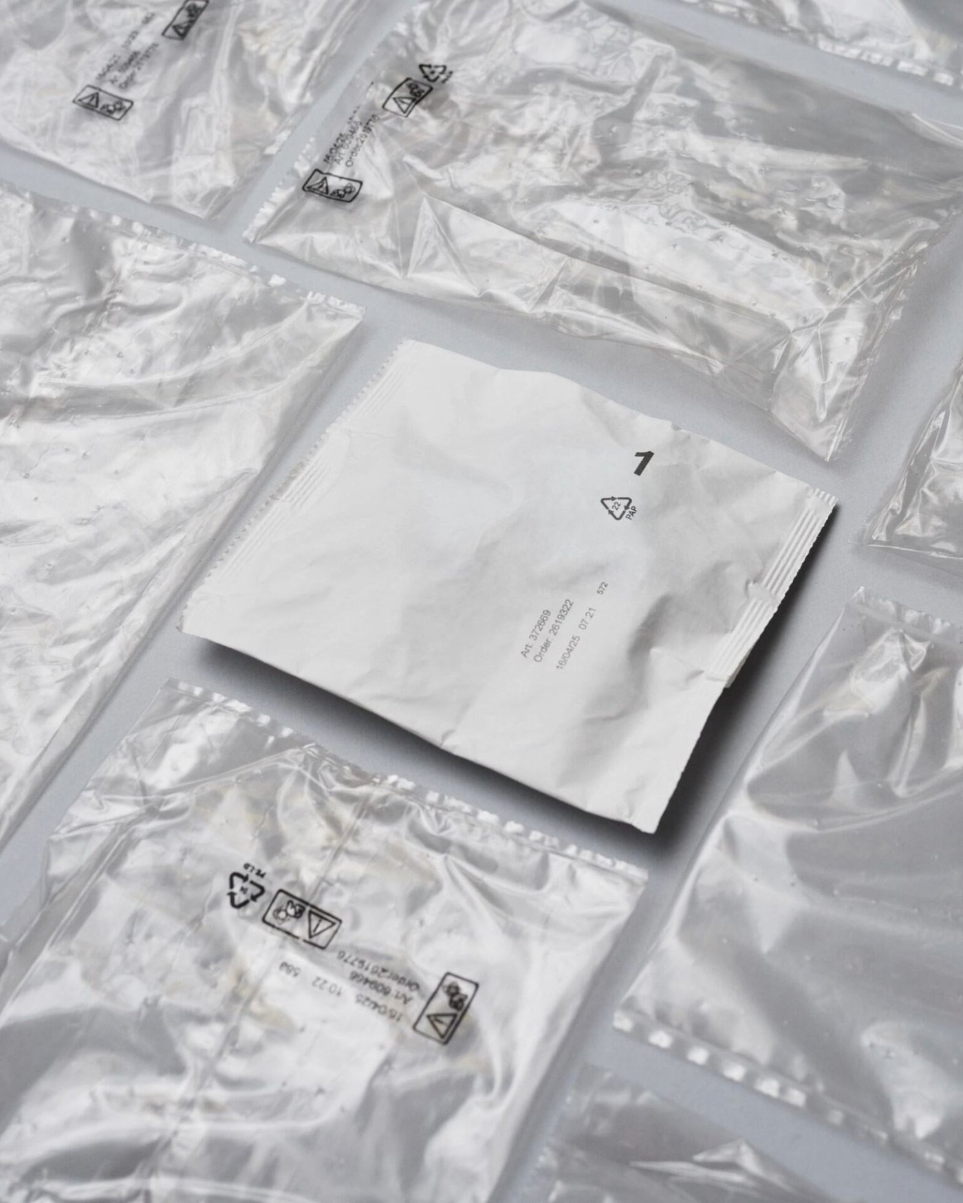 A paper-based fitting bag is lying flat down next to numerous plastic fitting bags.