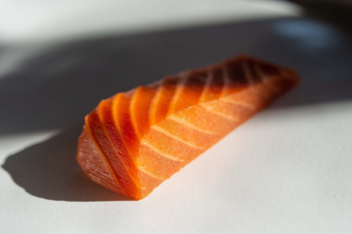 A fillet of New School Foods plant-based salmon, uncooked, placed on a white surface.