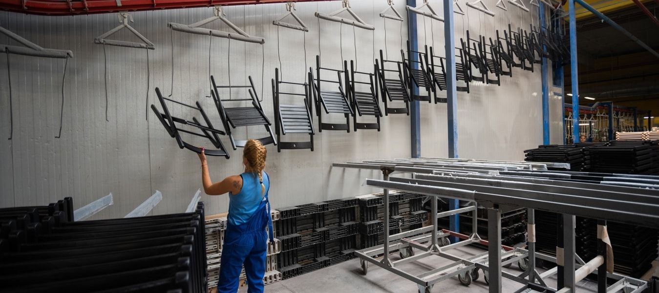 A person standing next to a row of chairs hanging up in front of a wall.