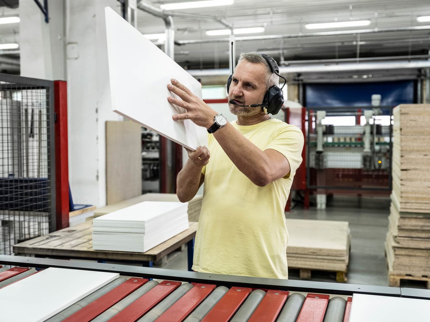 A factory co-worker closely inspects part of an IKEA product on the assembly line for quality.