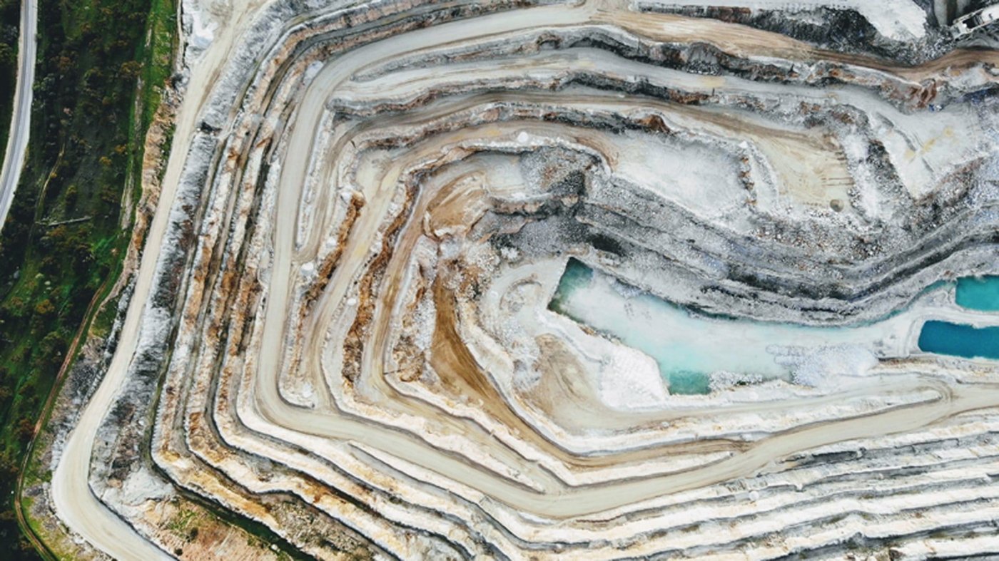 An aerial view of an open cut mine, with three blue-green pools of water at the bottom.