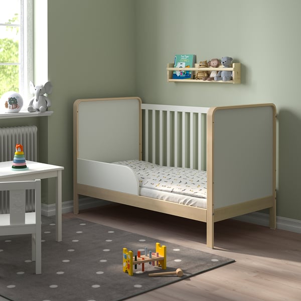 Green kids room with ÄLSKVÄRD cot, toys, and grey rug.