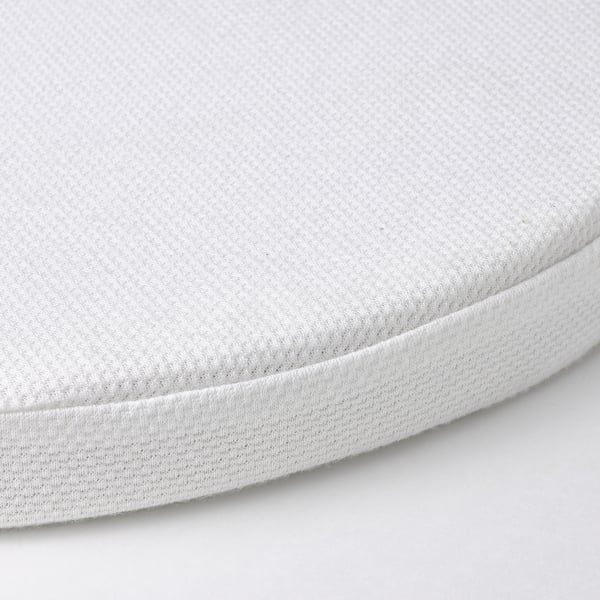 Close-up of a firm, white bassinet mattress with a textured cover, showing quality and comfort.