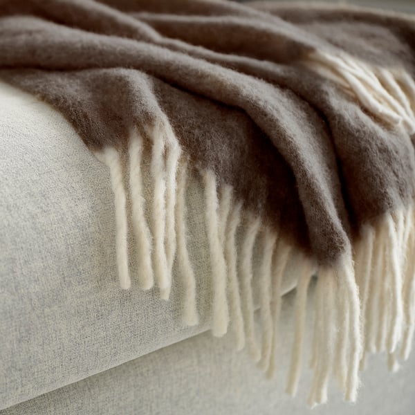 Soft, textured brown and white blanket draped over cushions.