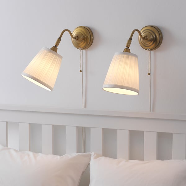 Two vintage-style wall lamps above a bed, with adjustable necks and beige shades, casting a warm light.